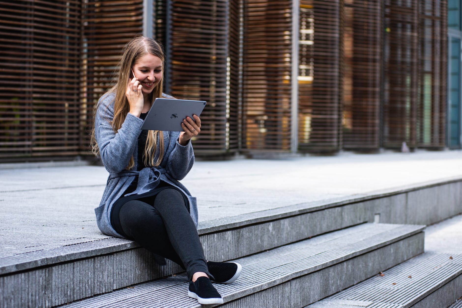 woman in gray cardigan holding black ipad outdoors