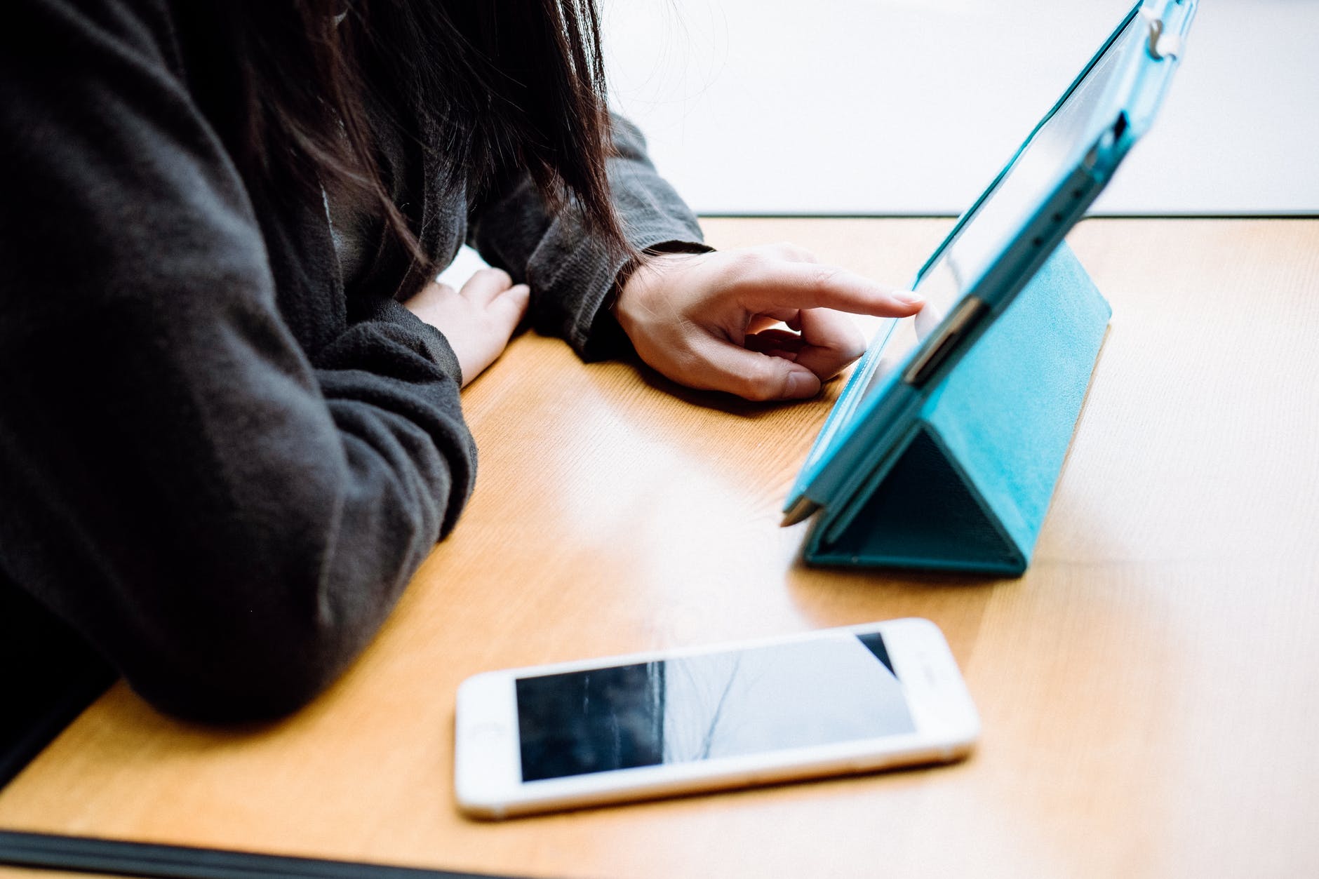 woman with phone and tablet on table